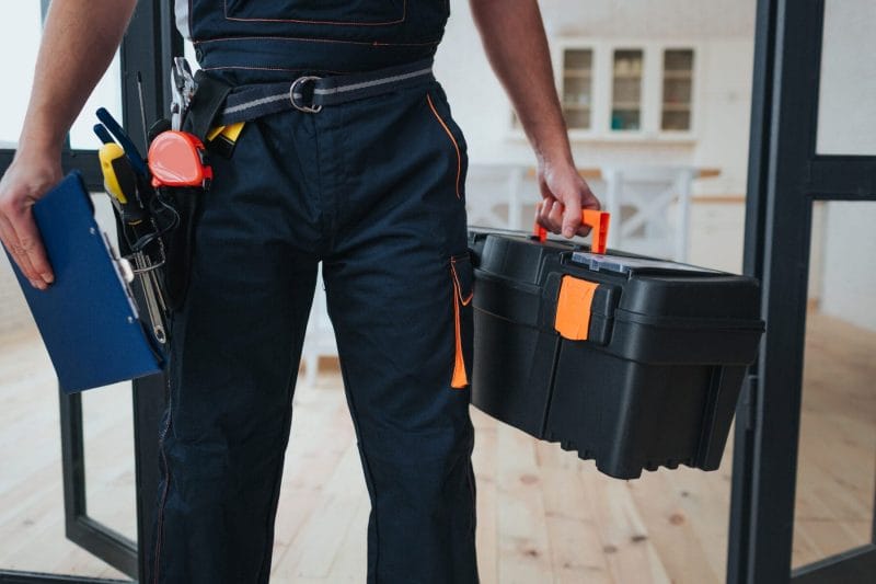 A handyman holding a toolbox and clipboard, ready to provide service in a home.