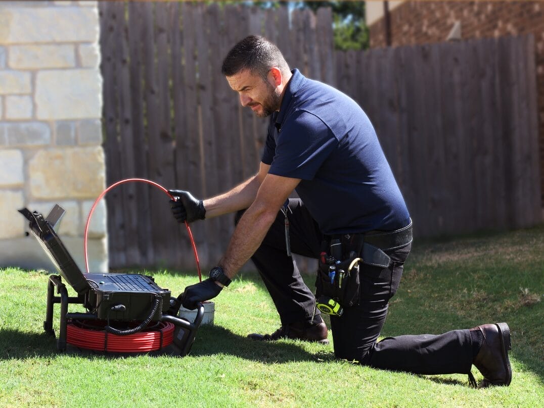 Home inspector performing a sewer scope inspection using specialized equipment in a residential backyard.