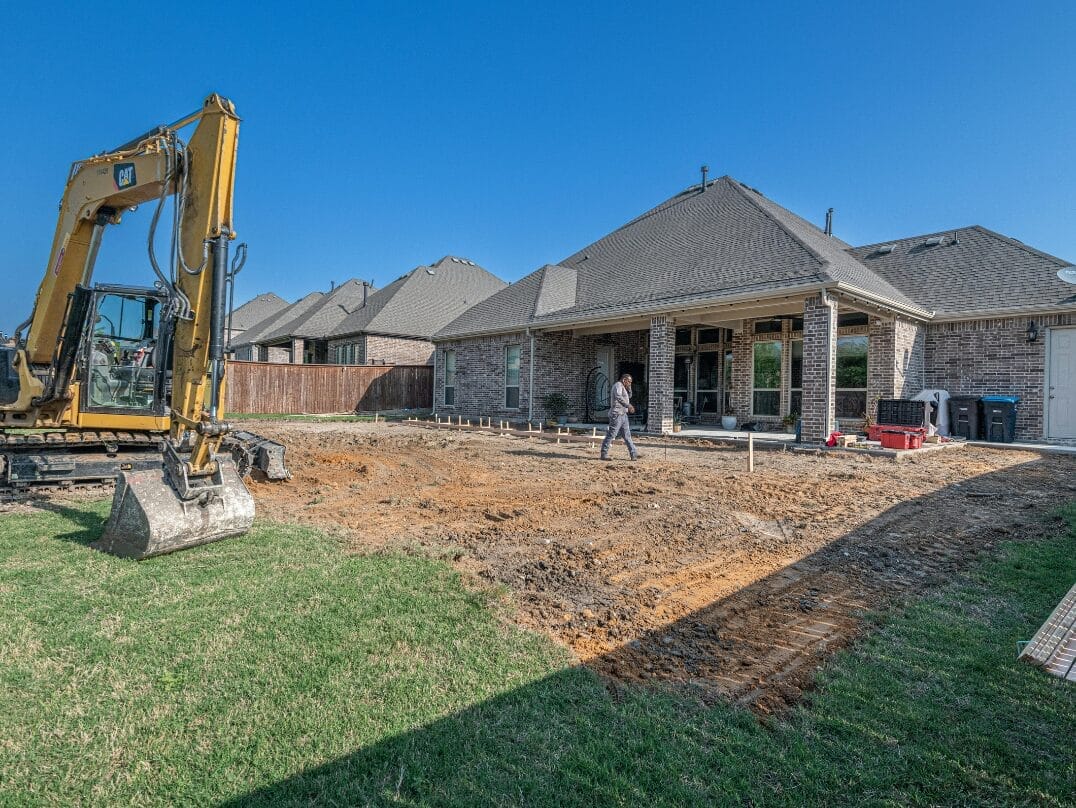 Excavator and worker preparing the foundation of a Texas home.